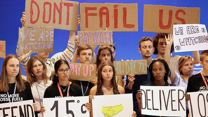 在COP27气候峰会上，年轻的气候活动人士举着写有“不要让我们失望”的标语。