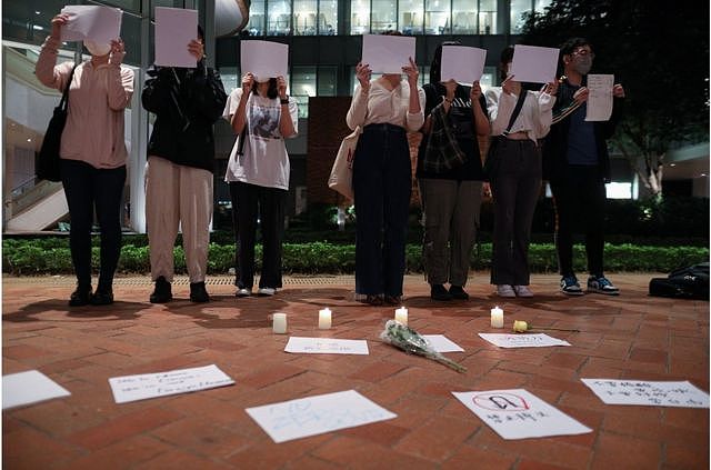 11月29日，在香港的大陆学生在香港大学为中国新冠“清零”政策受害者和乌鲁木齐大火的受害者守夜时高举着白纸。
