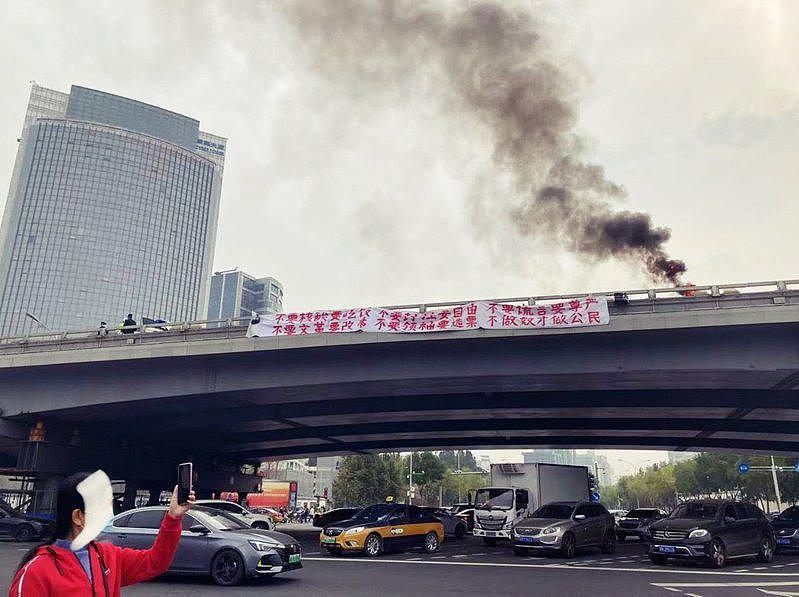 北京四通桥上出现一条横幅白布条，红字写着「不要核酸要吃饭，不要封控要自由」等标语...