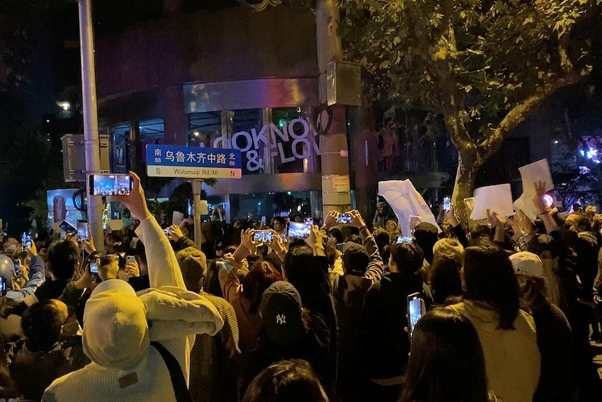 People take part in a nighttime protest in a city street.  