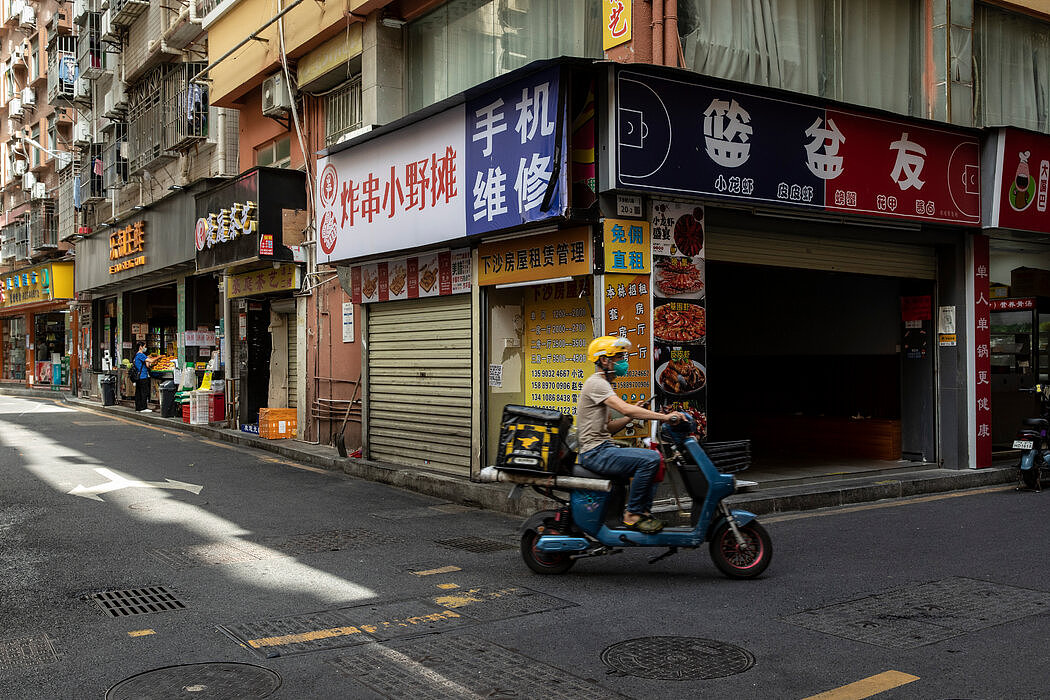 11月，在中国深圳的下沙村，一名送餐员骑车经过被关闭的商店。由于多次封锁，这里的许多企业要么停业，要么搬迁。