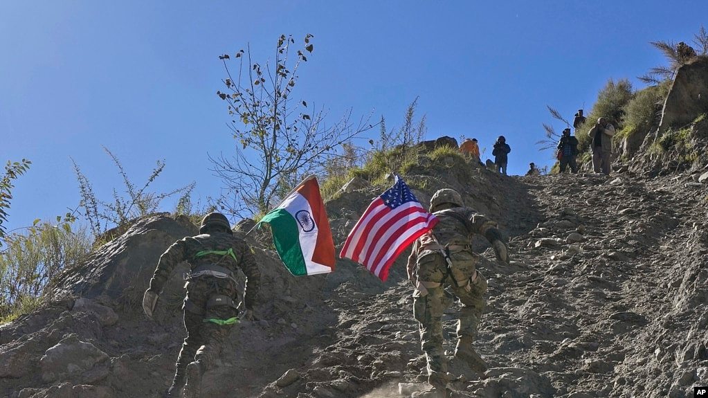 2022年11月30日，印度和美国陆军士兵举着各自国家的国旗，在印美联合演习期间跑上一座小山。 (美联社照片）