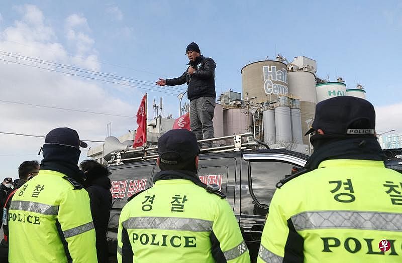12月1日，韩国仁川一家水泥厂外，警察包围一名在货车上讲话的工会卡车司机。（路透社）
