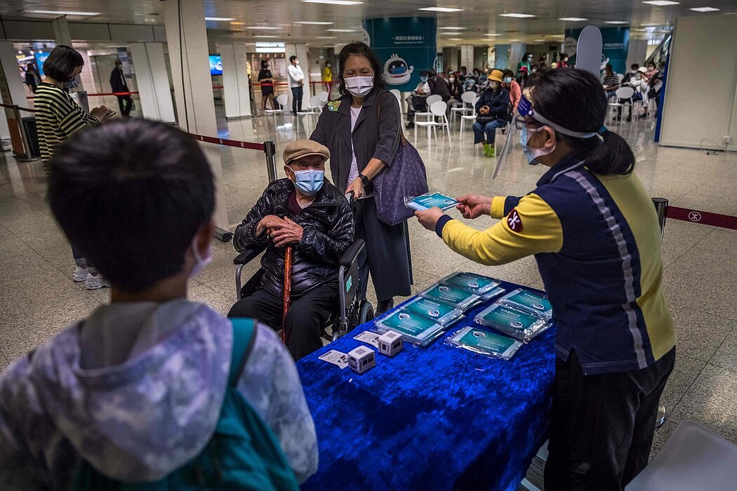 3月，在香港的一个疫苗接种点发放口罩。