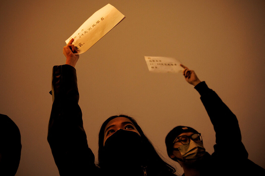 周日，北京，一场纪念乌鲁木齐火灾遇难者的守夜活动上，参加者手举白纸。