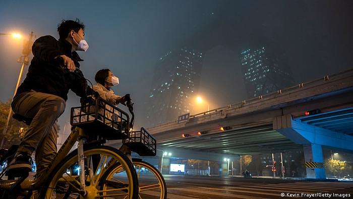资料照片：骑车路过央视附近的北京居民