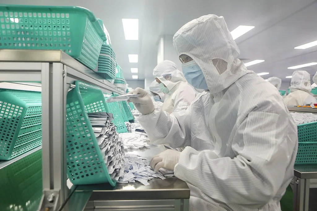 2022年2月21日，深圳某生物科技股份有限公司生产车间现场。工人在流水生产线上分组作业，生产新冠病毒抗原快速检测试剂盒。 人民视觉 图