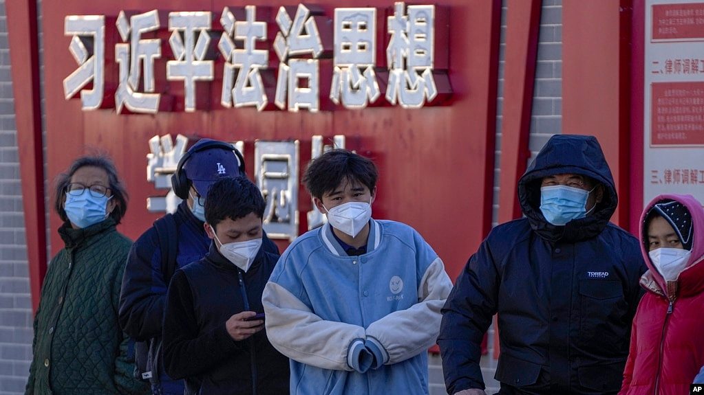 北京市民在宣传习近平思想的标语墙前排队等候进行核算检测。（2022年12月5日）