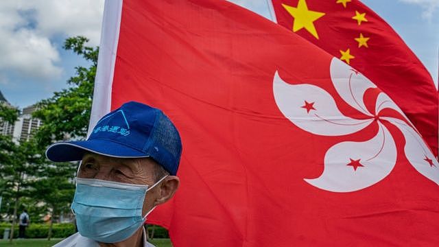 香港亲北京阵营庆祝北京颁布《香港国安法》活动上一位戴上口罩的老翁站在中国国旗与香港区旗前（30/6/2020）