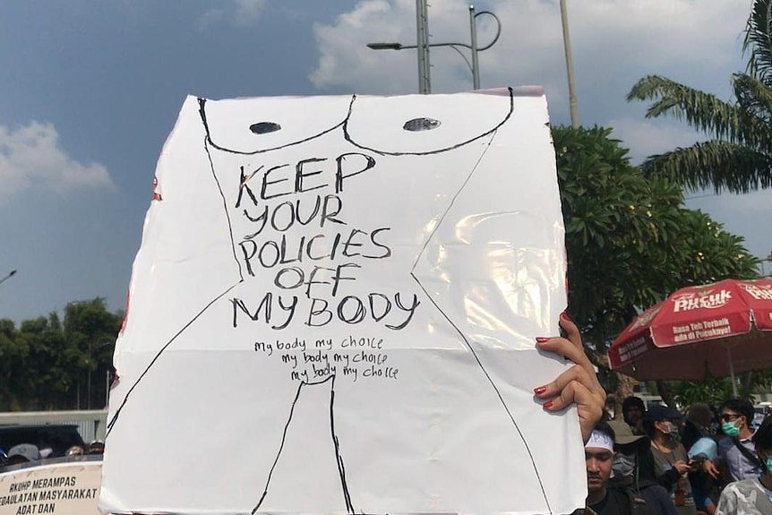A protester holds a sign reading' 'Keep your policies off my body' and 'My body my choice'.
