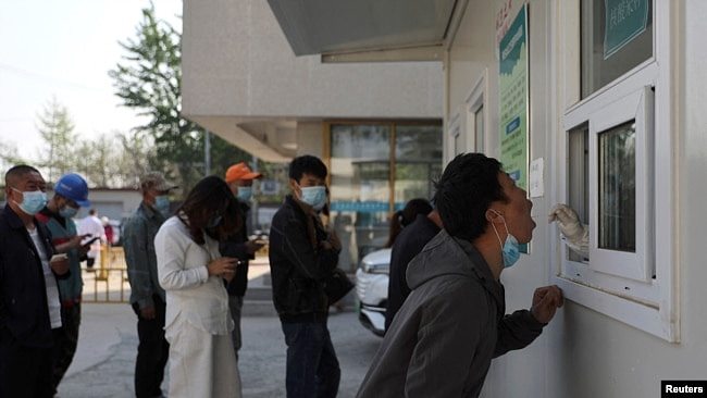 资料照片：在北京与河北省的交界附近的新冠病毒检测站，一位男子张开嘴接受检测。(2022年4月20日)