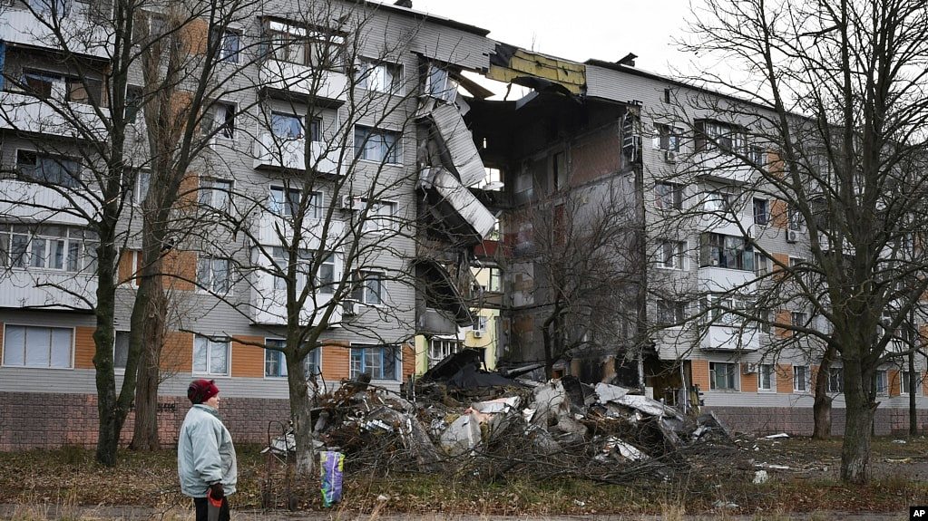 2022 年 12 月 11 日，在乌克兰顿涅茨克地区，一名妇女走过一栋被俄罗斯炮击损坏的公寓楼，巴赫穆特是与俄罗斯军队发生最激烈战斗的地点。