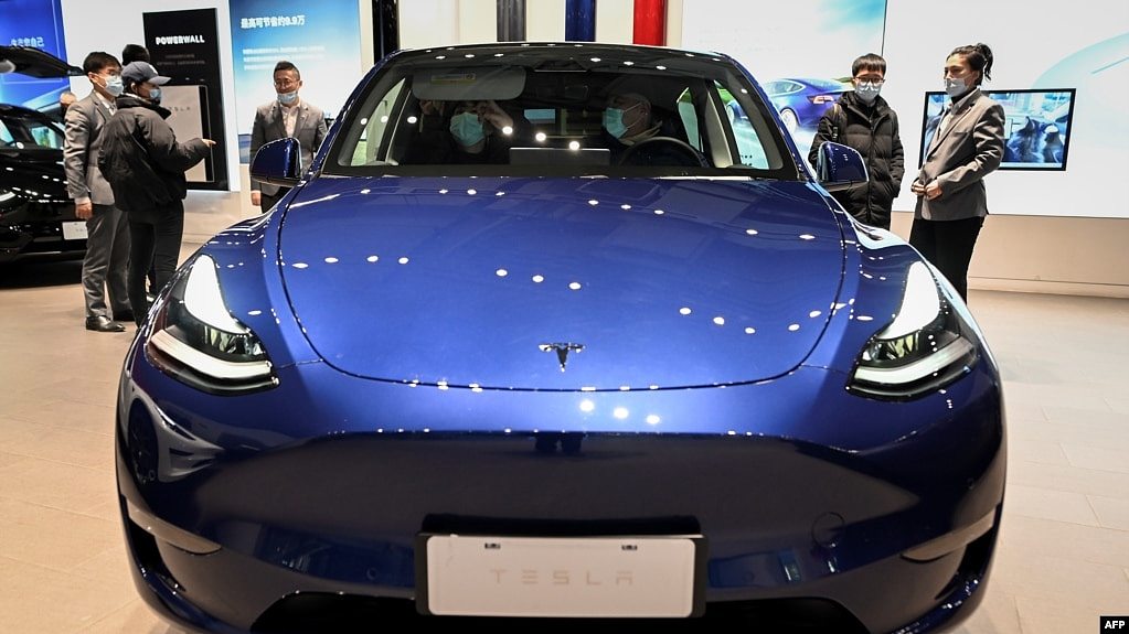 2021年1月5号北京车展上的特斯拉展厅，人们正在观看一辆蓝色特斯拉Y型电动轿车。