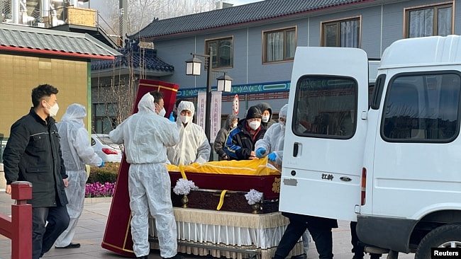 北京一家火葬场工作人员将灵柩移下车。（2022年12月17日）