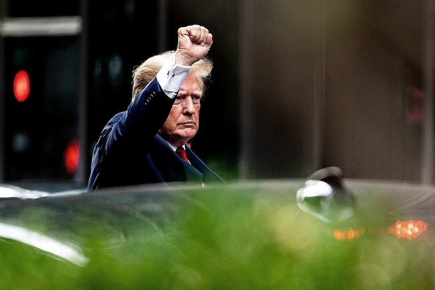 Donald Trump raises his fist as he leaves Trump Tower