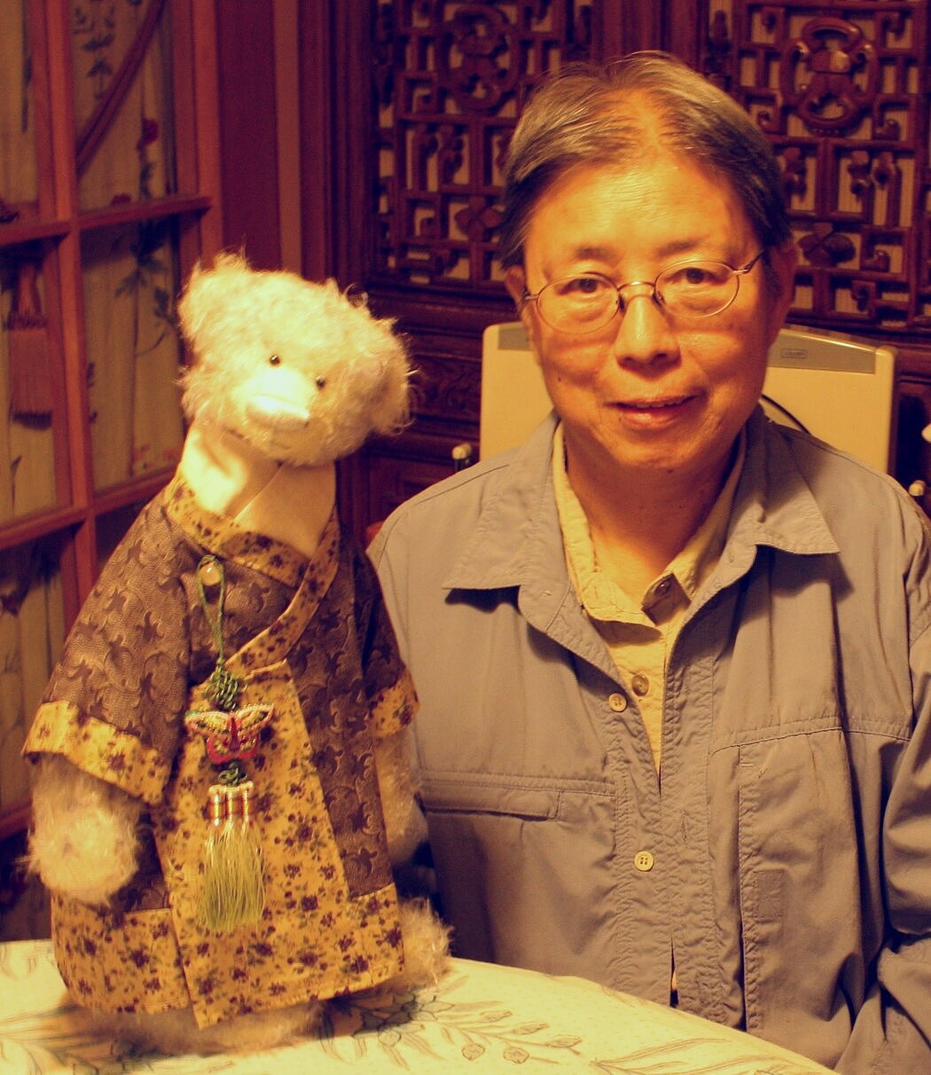 作家西西在香港的家中抱着一只泰迪熊，她在癌症治疗后开始把制作泰迪熊作为一种理疗，她把它们打扮成中国神话、文学和历史中的角色。
