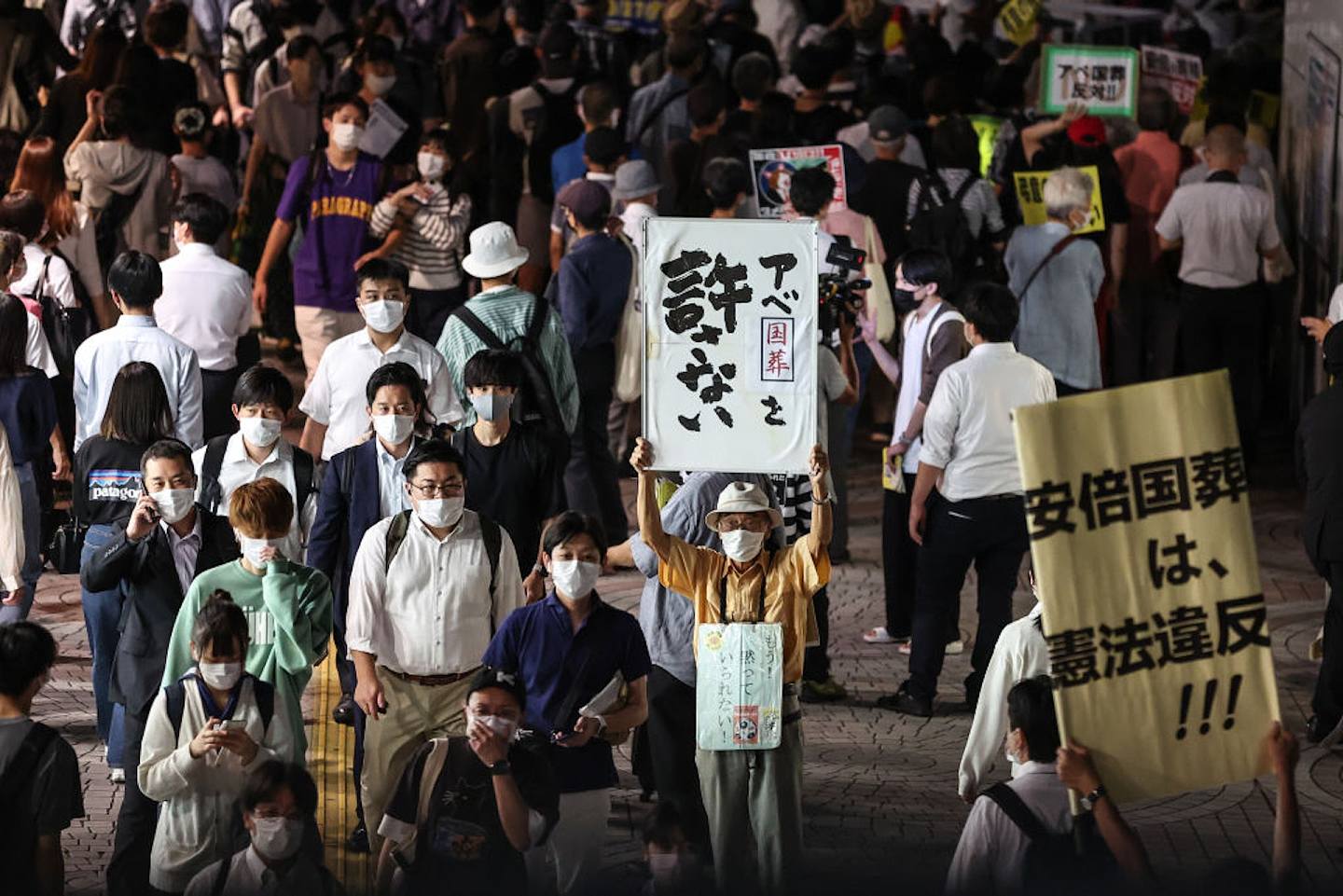 安倍晉三國葬：圖為2022年9月26日，反對為日本前首相安倍晉三舉行國葬的民眾在東京街頭手持標語牌示威。（Getty）