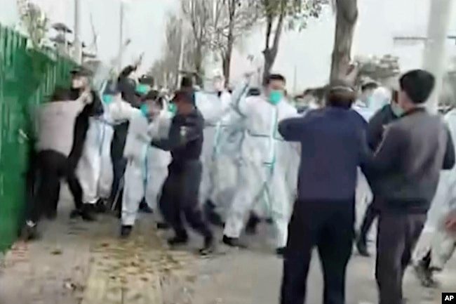 中国河南郑州富士康代工厂里身穿防护服的警察和保安殴打参加示威活动的工人。(2022年11月23日)