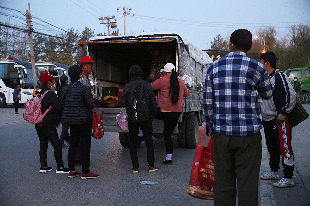 一群农民工4月20日清晨在河北省界附近登上卡车，被载往当天打零工的地点。(路透社)