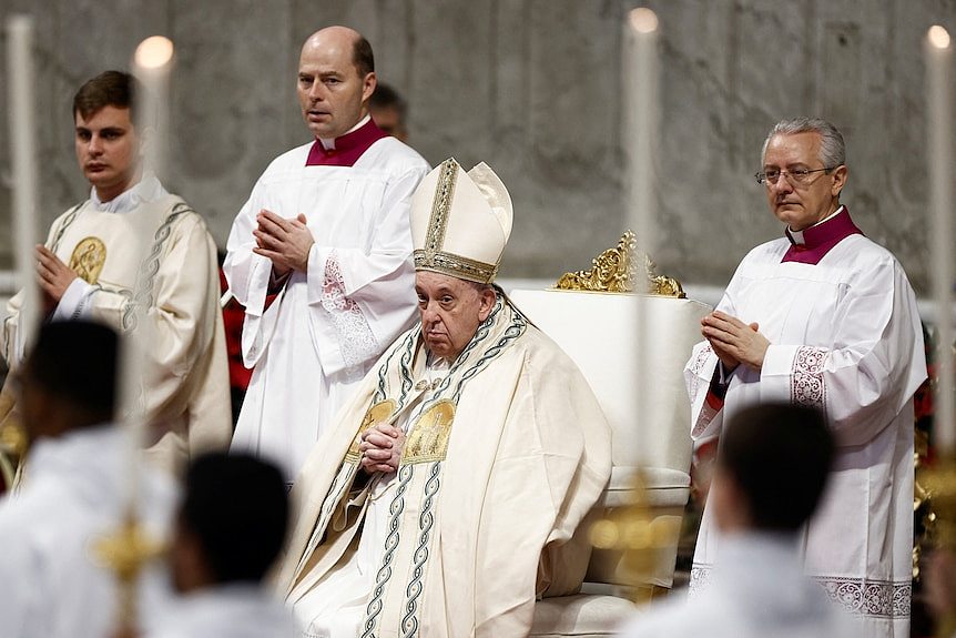 教皇弗朗西斯身穿长袍坐在金色椅子上，周围环绕着其他牧师。