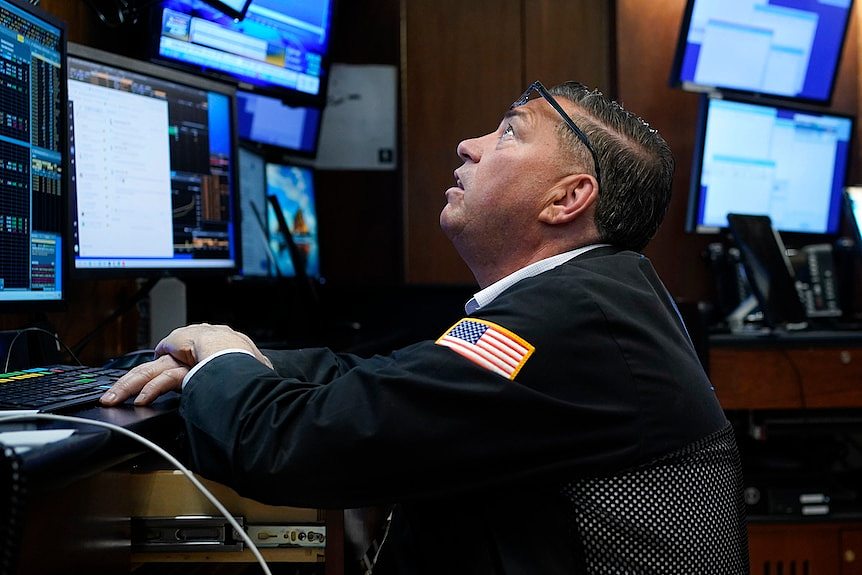 纽约证券交易所的一名交易员在办公桌后抬头看着电脑显示器