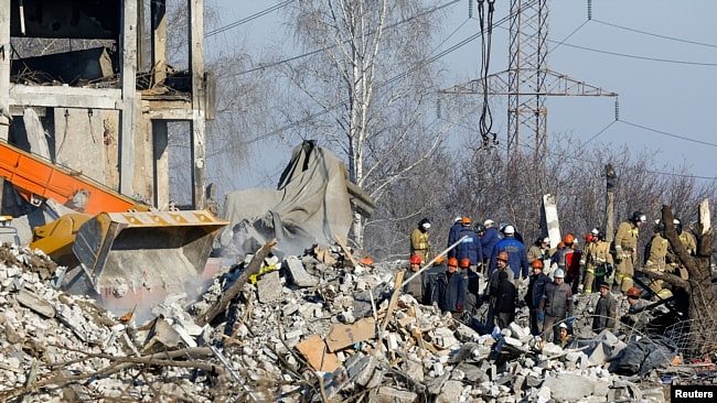 工人和紧急情况部门成员清除马克耶夫卡一座被毁建筑的残骸，据称这是一所用作俄罗斯士兵临时住所的职业学院。俄罗斯国防部表示，63人在乌克兰导弹袭击中丧生。（2023年1月3日）
