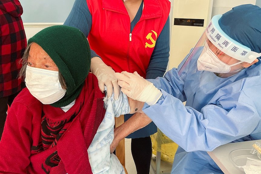 A medical worker administers a dose of a vaccine against COVID-19 to an elderly resident