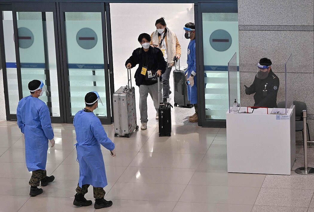 周二，在仁川国际机场，医护工作者引导从中国抵达韩国的旅客前往新冠检测中心。