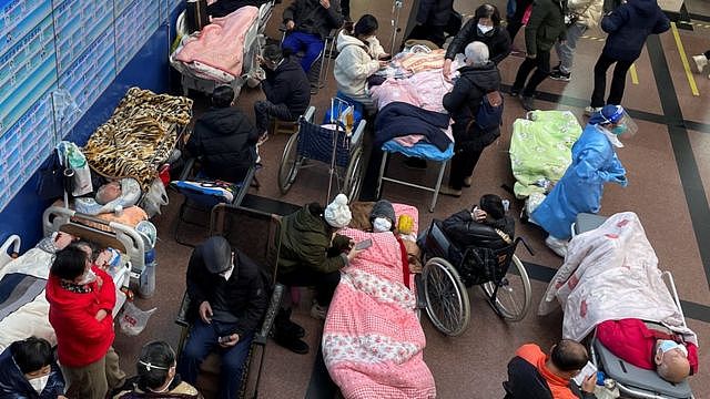 Patients lie on beds and stretchers in a hallway in the emergency department of a Shanghai hospital