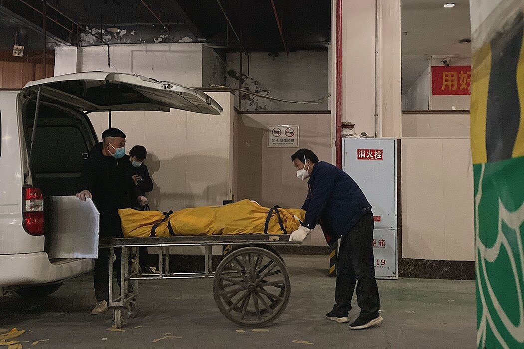 12月，在中国西南城市重庆，殡仪馆的工人们正在把遗体运至车上。