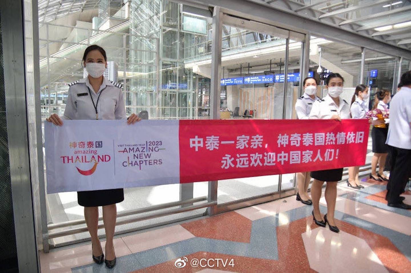 泰国机场有工作人员举旗子欢迎中国游客。 （微博）