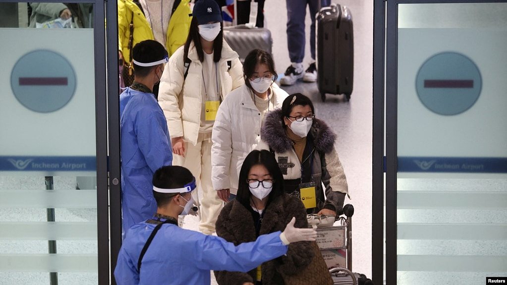 身穿防护服的韩国军人指引从中国抵达仁川国际机场的乘客进行新冠核酸检测。（2023年1月4日）