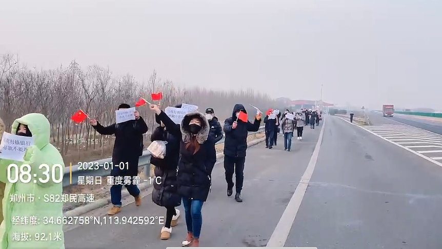 一群人沿着公路步行，手上举着标语