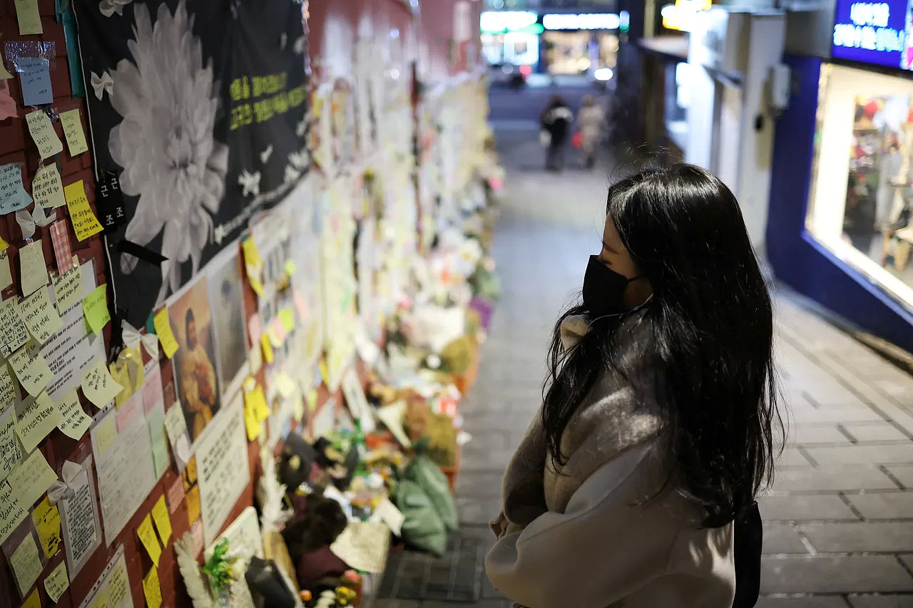 一名女子在泰梨院事故现场的悼念墙，追悼踩踏罹难者。 路透社