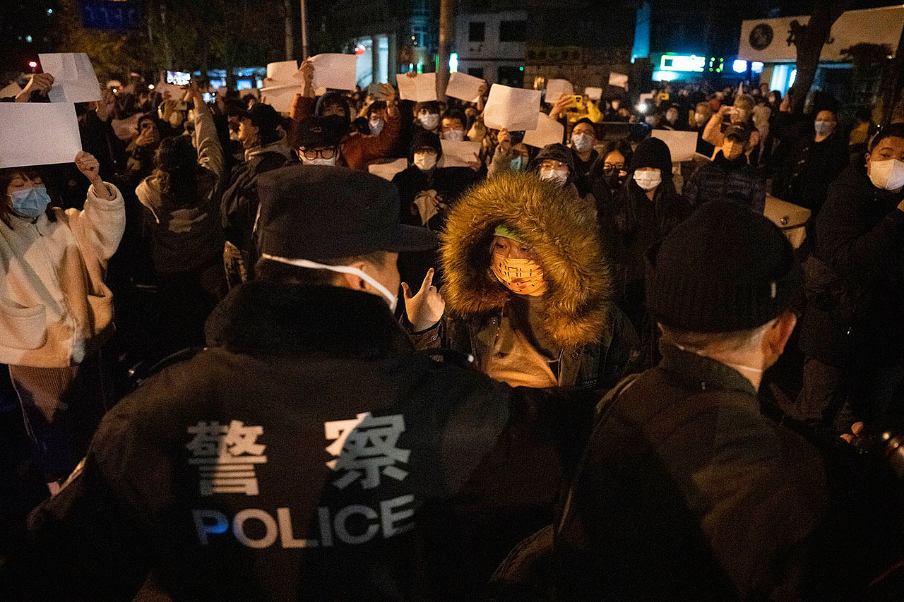 2022年11月27日，中国警察在北京与举着白纸的抗议者对峙。（美联社）