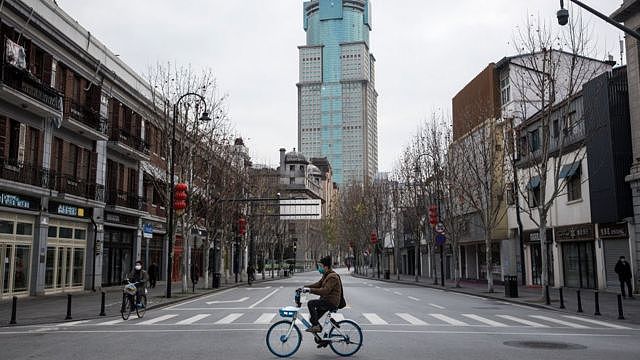 2020年2月8日，一名男子骑自行车经过湖北省武汉市一条空荡荡的街道。