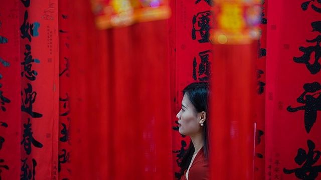 广西南宁一名妇女在即将到来的中国农历新年前购买红灯笼和对联装饰