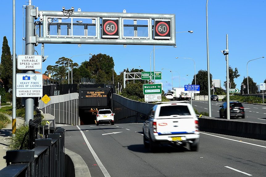 cars driving  towards the entrance of a tunnel