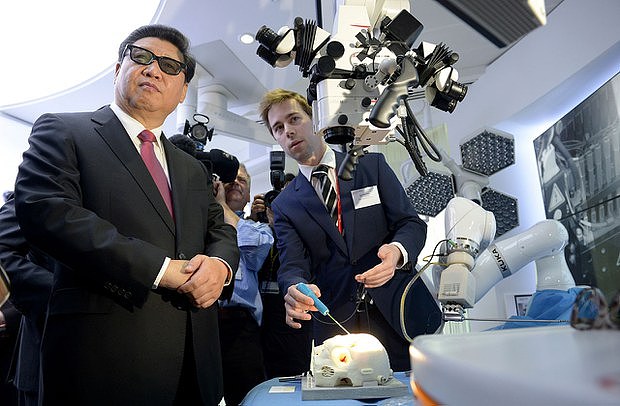 2015年10月21日，中国国家主席习近平（中）在访问英国伦敦帝国理工学院期间戴着3D眼镜在哈姆林医疗机器人中心观看机器人设备。（路透社图片）