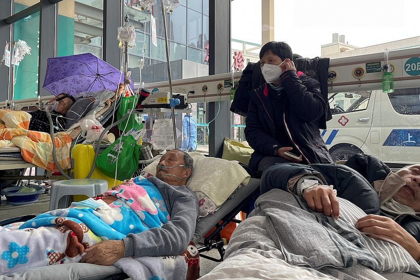 Patients lie on beds in the emergency department of a hospital.