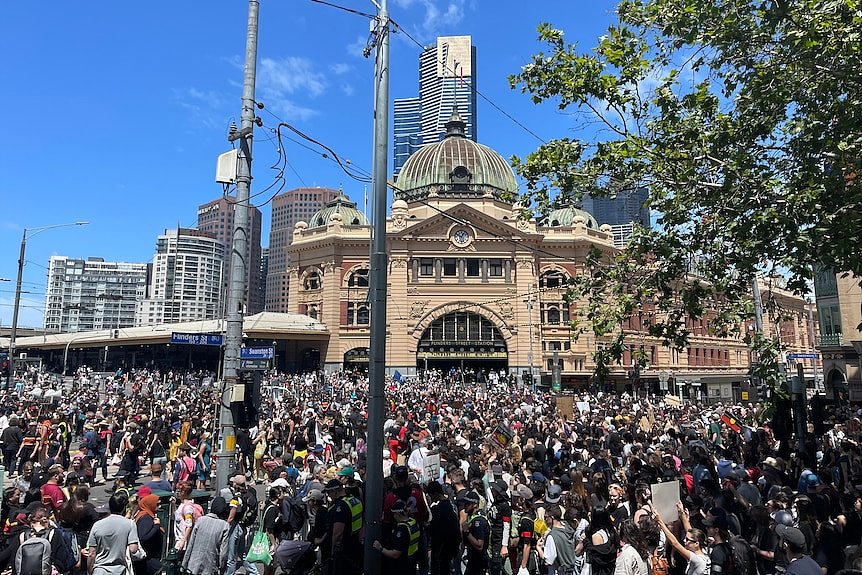 A large crowd of people outside Flinders Street Station in Melbourne.