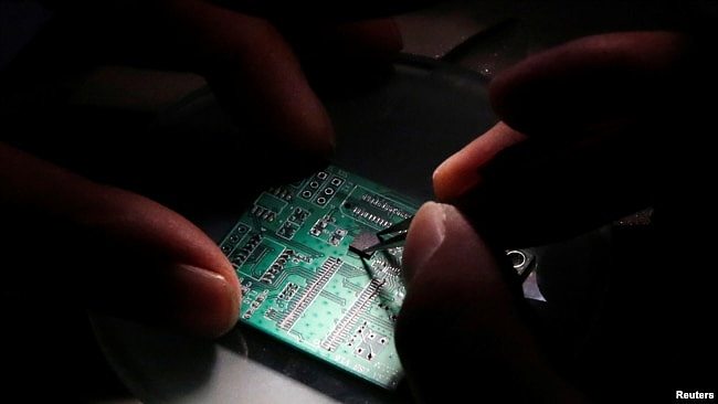 资料照：北京紫光集团研究中心的一名研发人员正在一片半导体接口板上工作。（2016年2月29日）