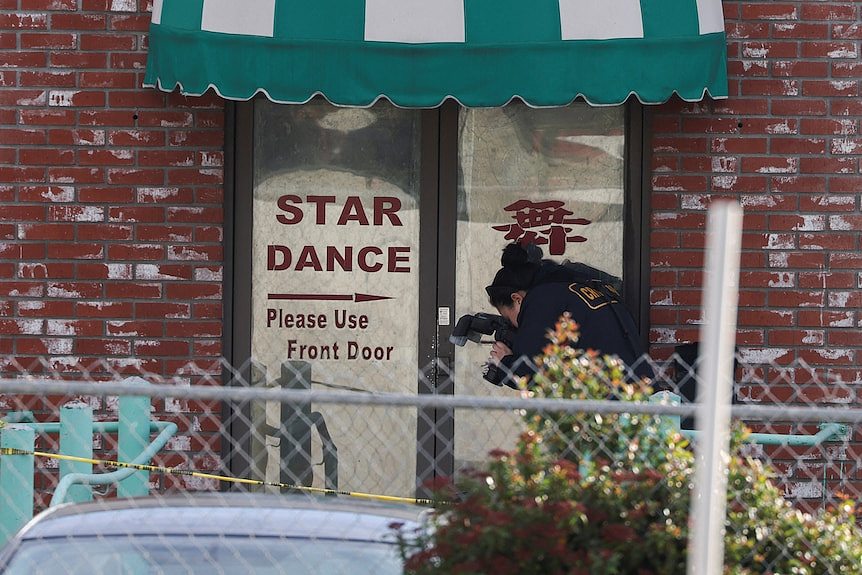 Person takes photos of entrance of ballroom dance hall at the centre of a mass shooting.
