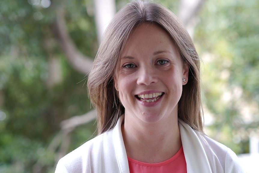 Headshot of smiling woman in white jacket and pink-ish top