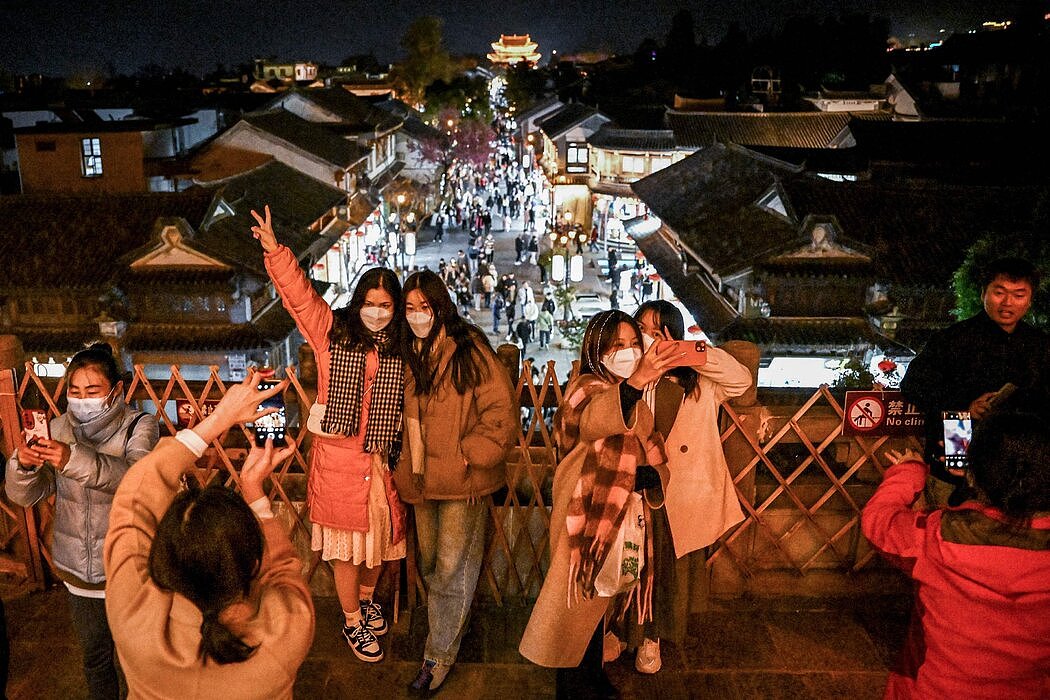 本月早些时候，在中国云南省大理县城欢庆的人群摆姿势拍照，当时正值新冠限制措施刚放松不久。