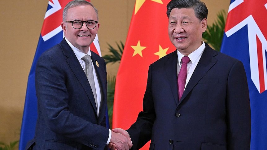 Anthony Albanese and Xi Jinping shake hands in front of chinese and australian flags