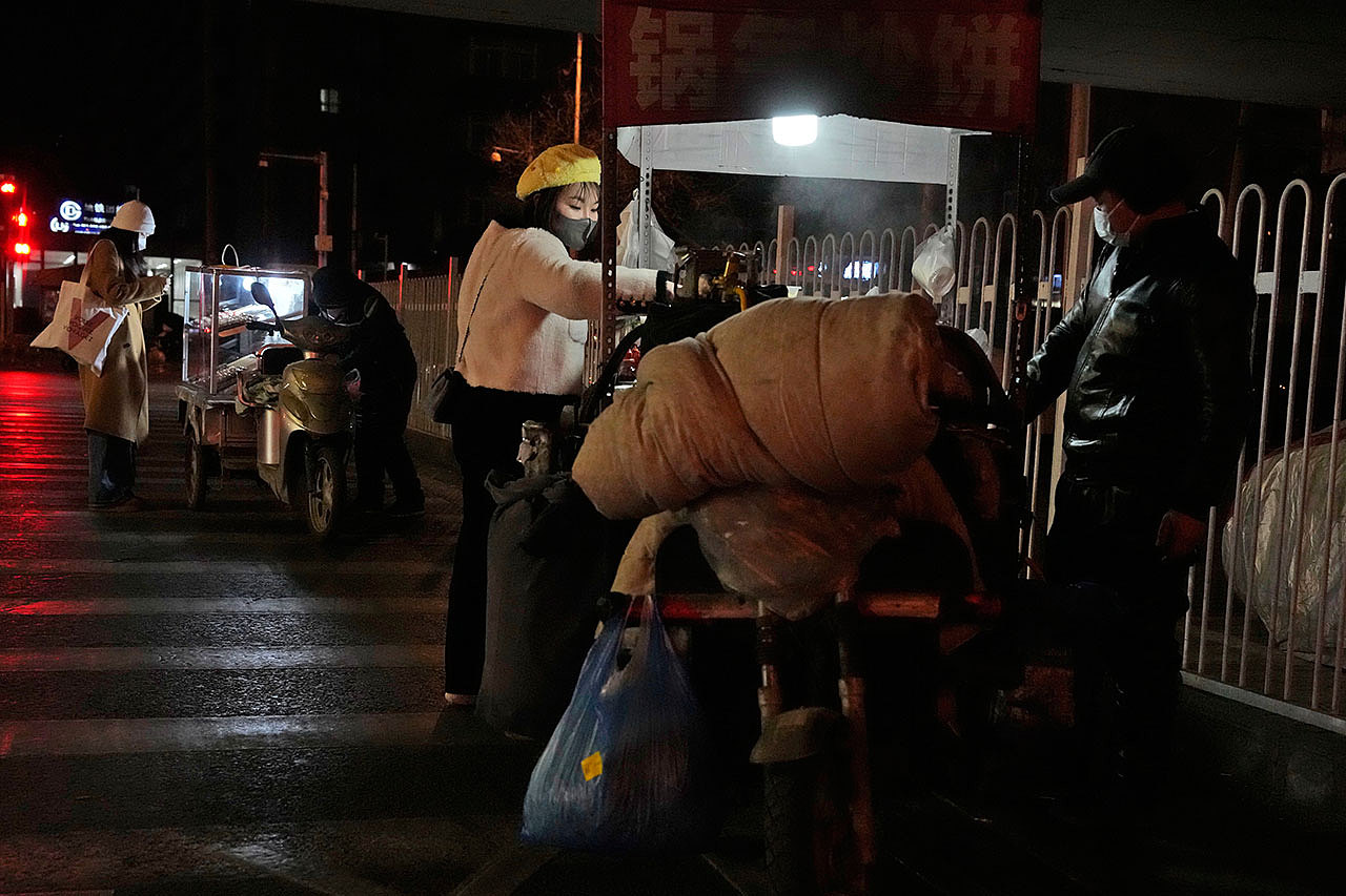2022年12月28日，一名居民从北京街头小贩那里购买小吃。（美联社）