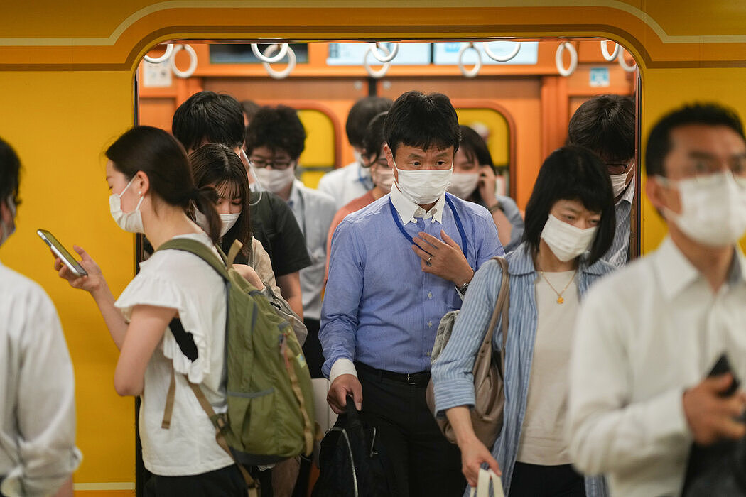 通勤者走进东京新桥站。大多数日本人在室内外都戴口罩。