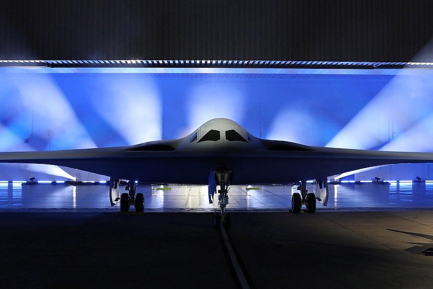 a stealth bomber is shown on a stage and is lit from behind 