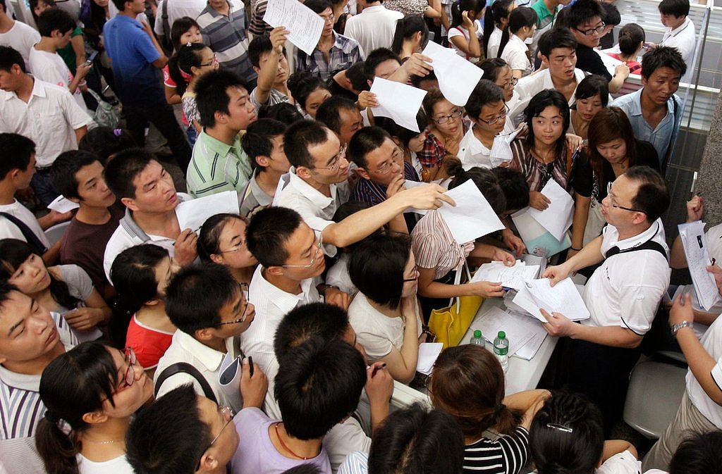 2010年中国河南省的一个工作招聘会上，应聘者蜂拥在富士康科技公司的展台前。